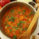 Large pot of cabbage soup with a wooden spoon on top of the pot.