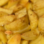 Sliced up cooked potatoes with spices.