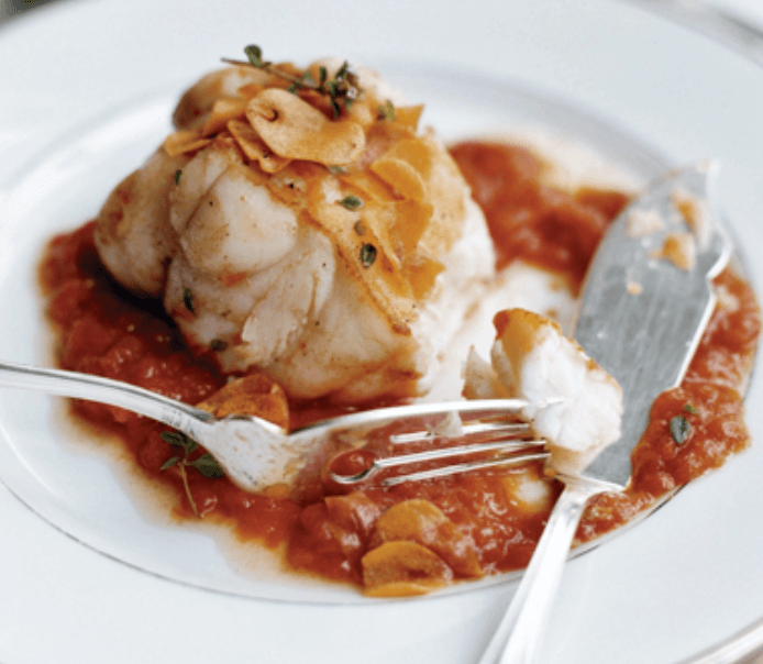 A plate of monkfish with tomato garlic sauce