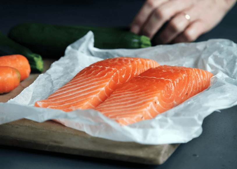 Two salmon fillets on top of white wrapping.