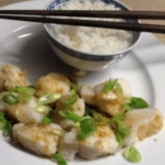 Steamed monkfish with ginger and spring onions served with a bowl of white rice.