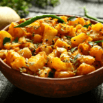 A large bowl filled to the top with a bright eggplant and potato curry.