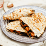 Black beans and sweet potato quesadilla on a grey and white plate.