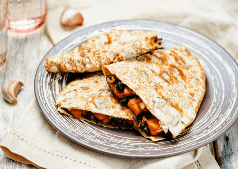 Black beans and sweet potato quesadilla on a grey and white plate.