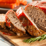 Slices of meatloaf on wooden cutting board.