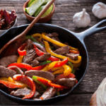 Mushroom, peppers, and steak fajitas in a skillet.