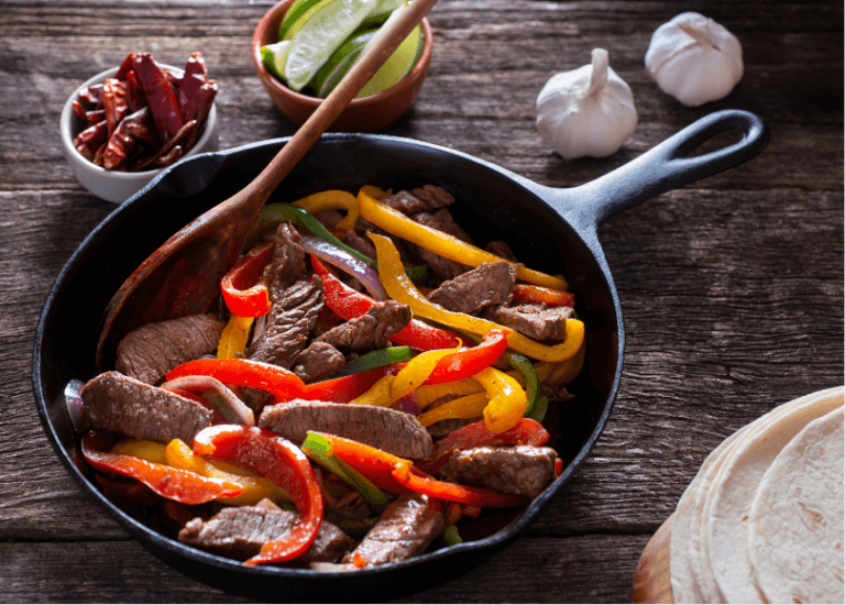 Mushroom, peppers, and steak fajitas in a skillet.