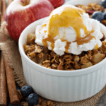 Microwave Fruit Crisp in a small white cup topped with ice cream and caramel
