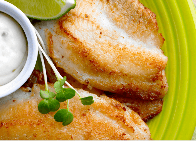 Tilapia with lime and dip on a green plate.