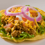 Turkey Tostadas with lettuce, tomato, red onion, cheese, and sour cream.