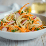 Apple, carrots, onion, fennel slaw in a white bowl.