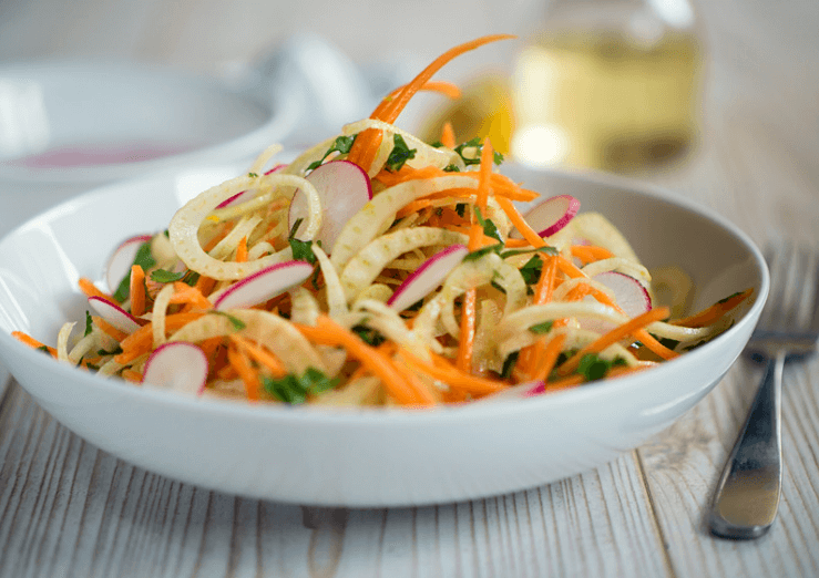 Apple, carrots, onion, fennel slaw in a white bowl.