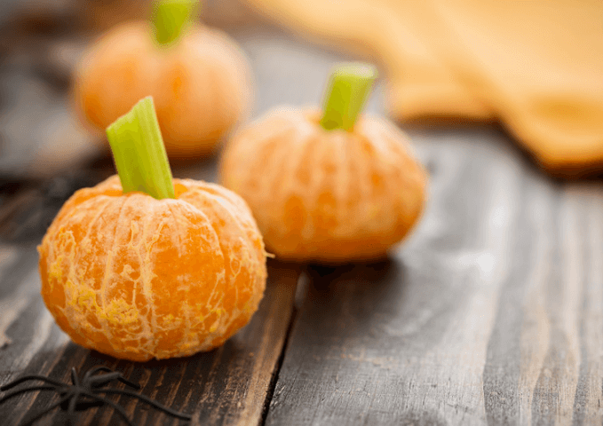 Three clementine's with celery stalks to resemble pumpkins.