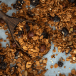 Homemade granola with raisins on a baking sheet.