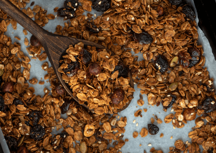 Homemade granola with raisins on a baking sheet.