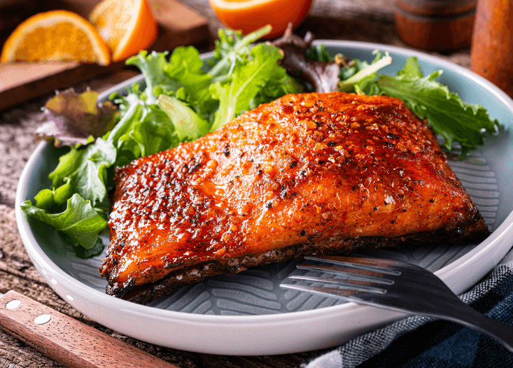 Honey glazed salmon with lettuce and orange slices.