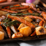 A baking tray full of roasted root vegetables and spicy pecans