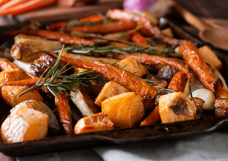 A baking tray full of roasted root vegetables and spicy pecans