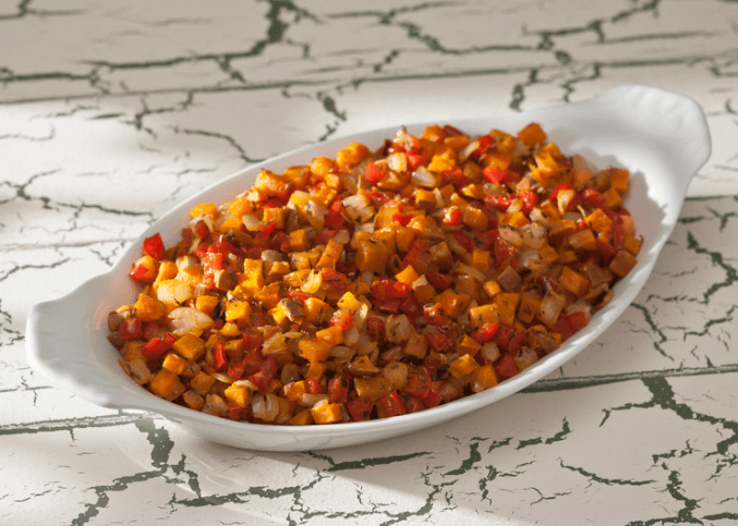diced sweet potatoes, apples, and red peppers in a baking dish.