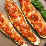 Three halves of whole zucchini with cheese and sauce as pizza boats.
