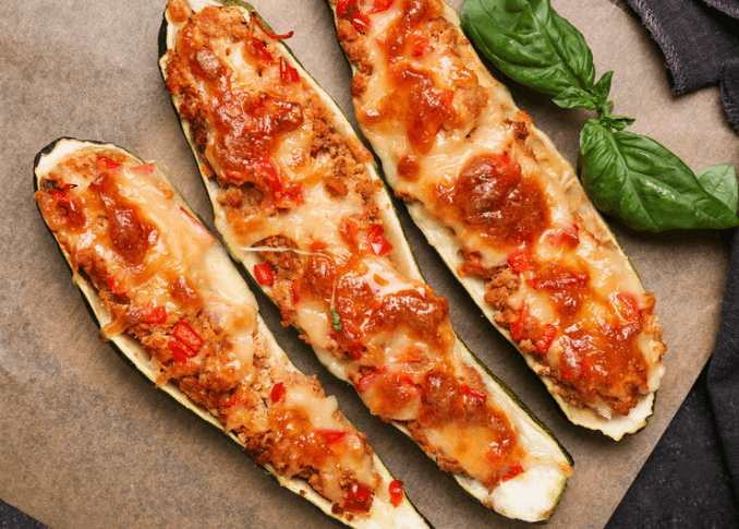 Three halves of whole zucchini with cheese and sauce as pizza boats.