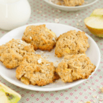 Oatmeal cookies on a white plate with halved apples.