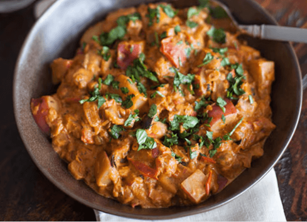 Eggplant and diced potatoes curry in a dark bowl.