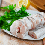 Cut mackerel on a white plate with a knife.