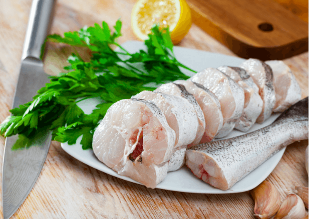 Cut mackerel on a white plate with a knife.