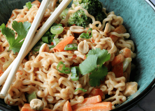 Ramen noodles with chop sticks, carrots, broccoli, and peanuts.