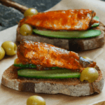 Toasted bread with cucumber and seasoned sardines on top.