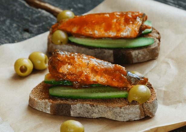 Toasted bread with cucumber and seasoned sardines on top.