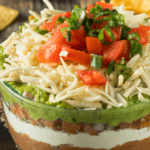 Tomatoes, cheese, guacamole, beans, sour cream layered dip.