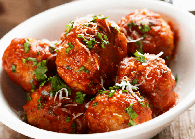teriyaki meatballs with herbs in a white bowl.
