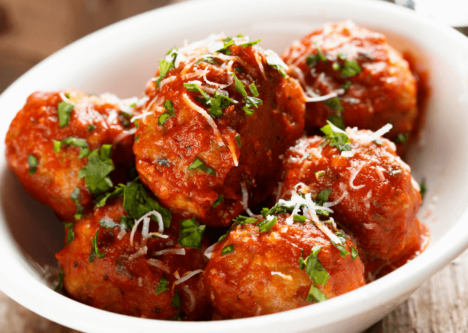 Teriyaki meatballs with herbs in a white bowl.