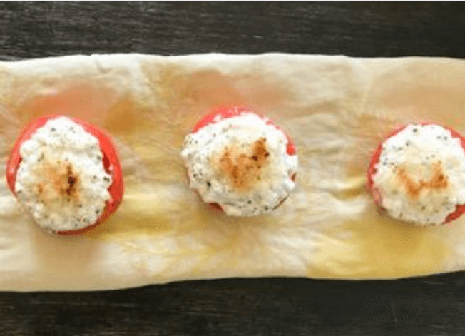 Three tomatoes and cheese on parchment paper.