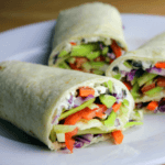 Three vegetable wraps on a white plate.