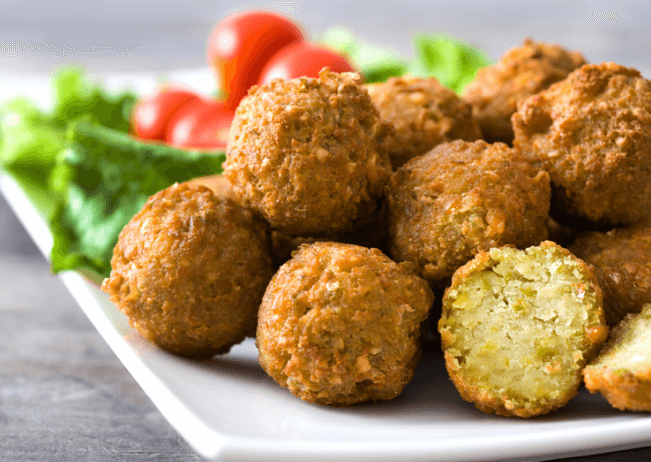 Stacked falafel balls with lettuce and tomatoes.