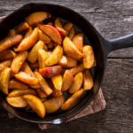 Sliced cinnamon apples in a black skillet.