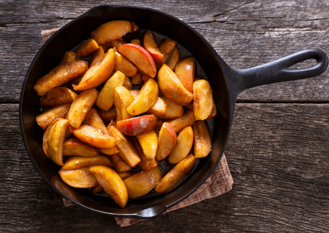 Sliced cinnamon apples in a black skillet.