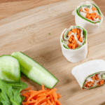 Three pin wheels filled with lettuce, carrots, and cucumber.