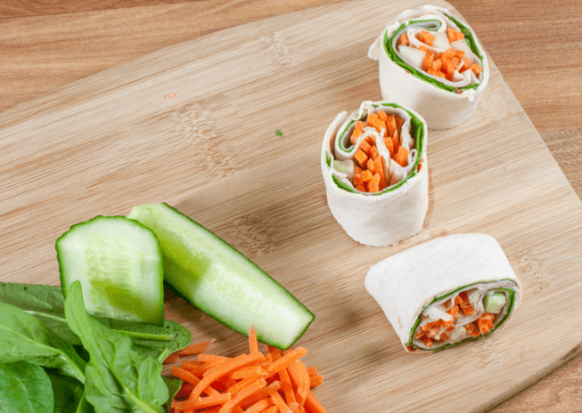 Three pin wheels filled with lettuce, carrots, and cucumber.