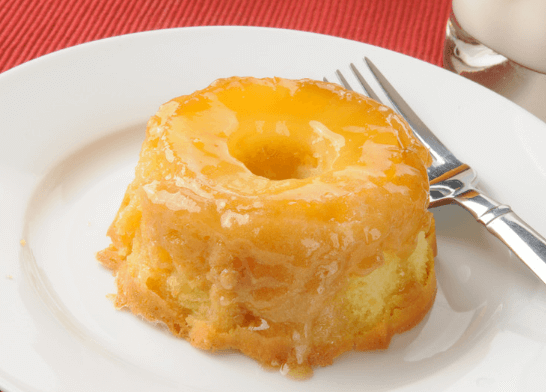 Upside down pineapple cupcake on a white plate.