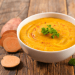 Sweet potato sliced next to a bowl of soup.