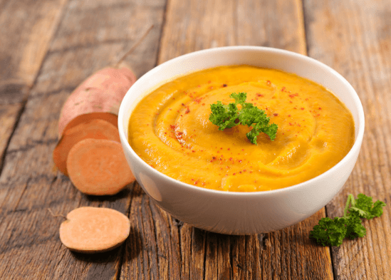 Sweet potato sliced next to a bowl of soup.