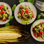 Okra, corn, tomato salad next to a corn on the cob.