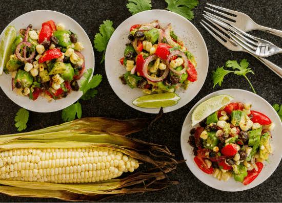Okra, corn, tomato salad next to a corn on the cob.
