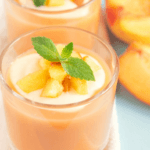 Peach smoothie with sliced peaches next to the glass.