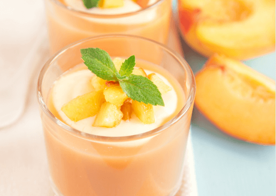 Peach smoothie with sliced peaches next to the glass.