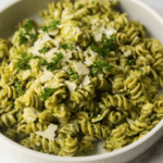 Spiral pasta with green sauce and shredded parmesan.